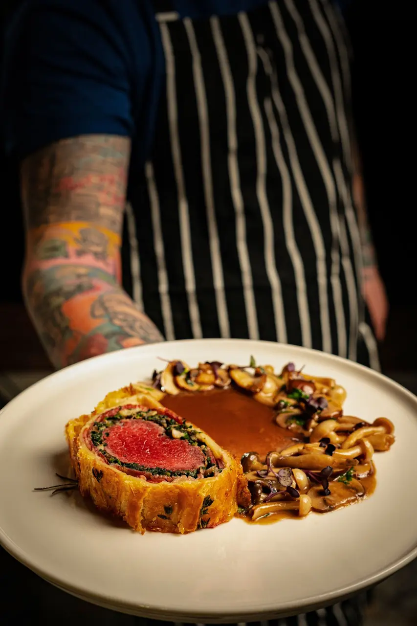 Chef meticulously plating a signature beef Wellington for a private event